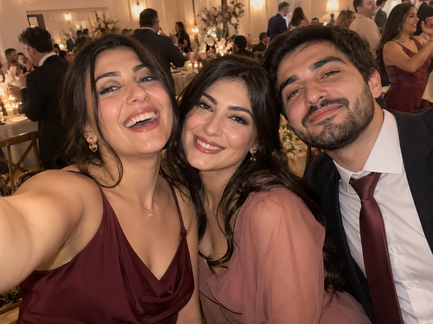 A spontaneous phone selfie of three friends laughing together at a wedding