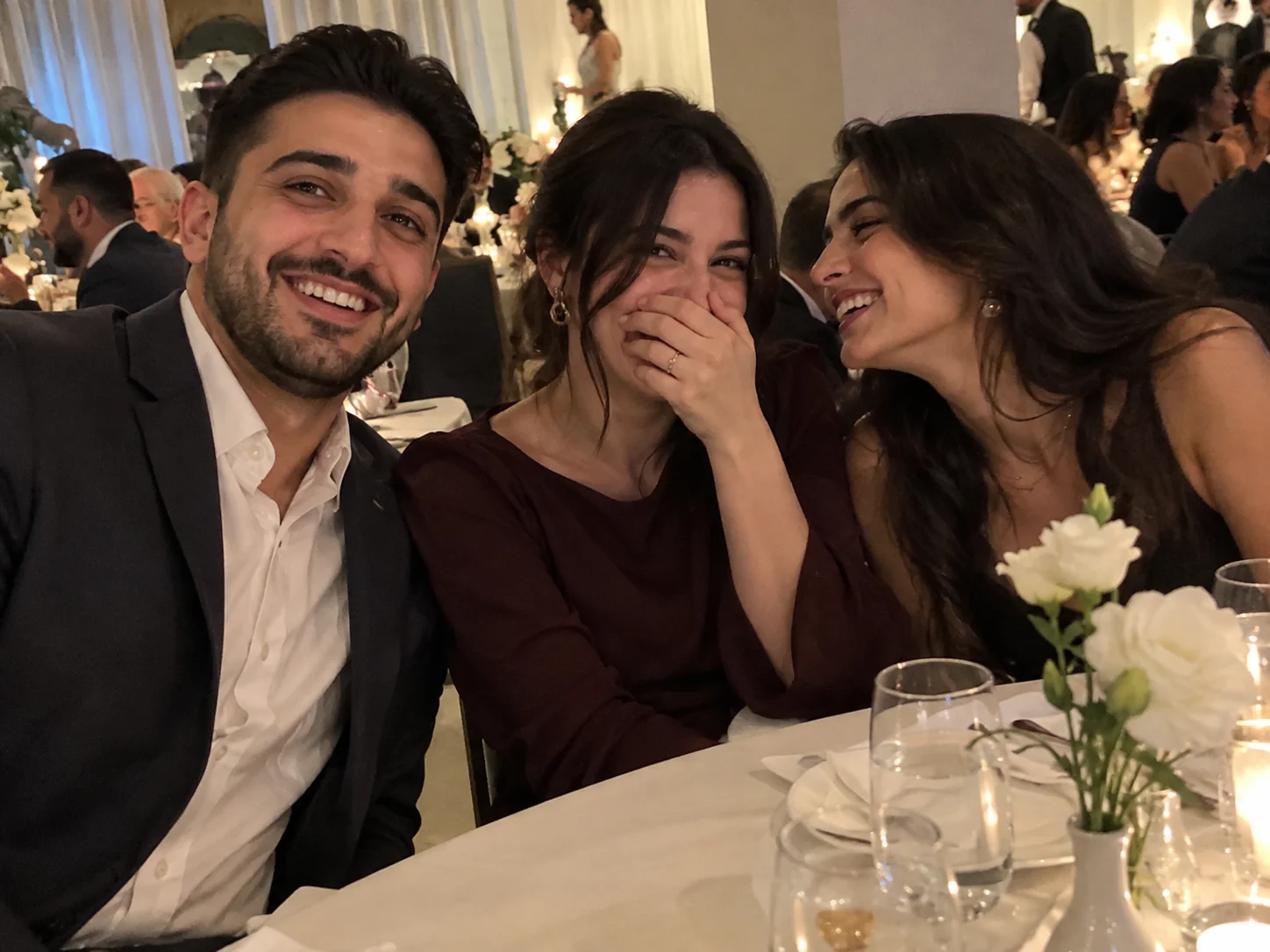 A guest's phone photo of friends bursting into laughter at a wedding table